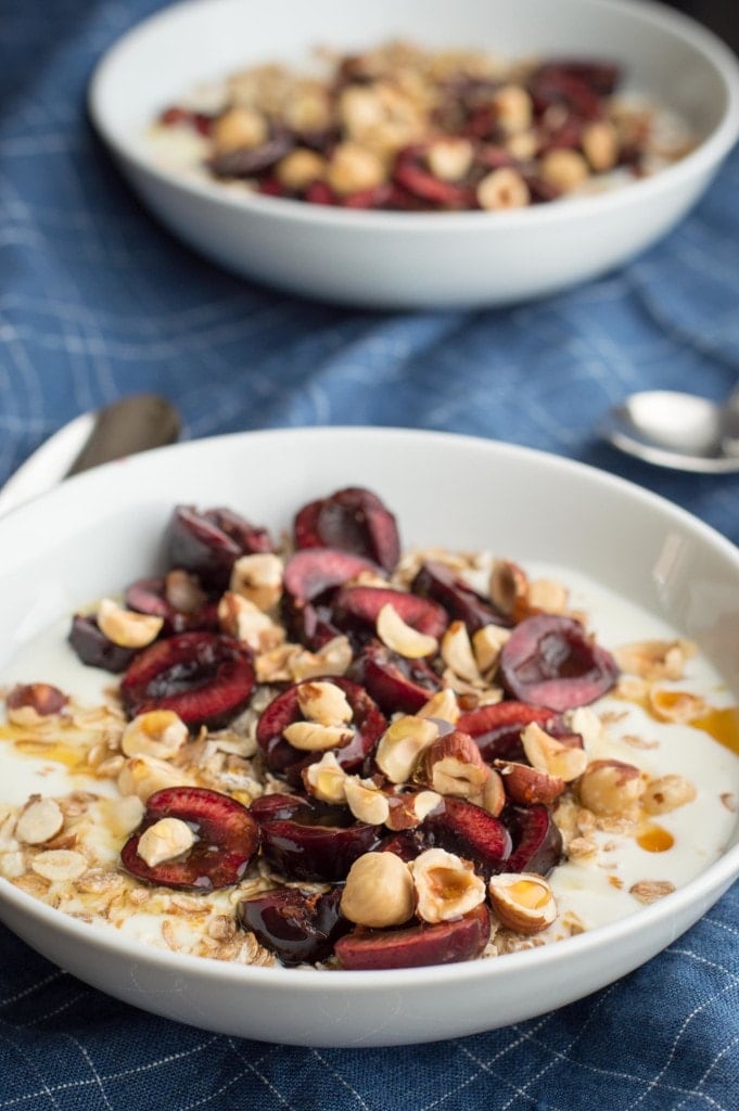 fresh cherry breakfast bowl with yogurt, hazelnuts, oats, and honey